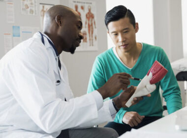 Doctor and patient examining bone model in clinic
