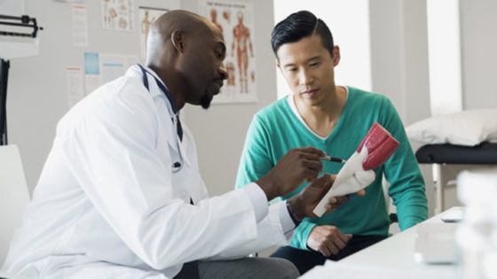 Doctor and patient examining bone model in clinic