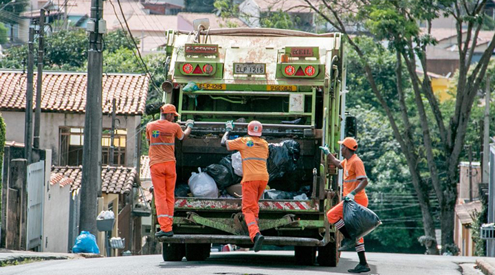 Coletores em caminhão de lixo atuam em rua da cidade