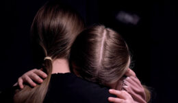 Mother hugging frightened little girl in dark room, victims of m