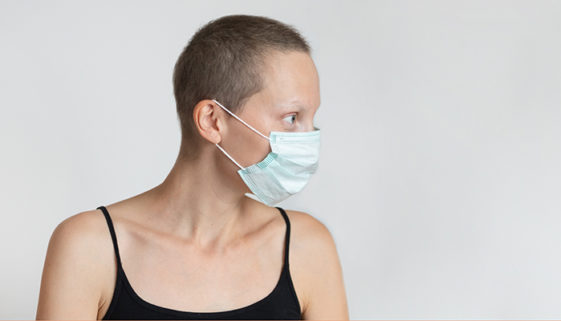 Profile side view of short haired young adult woman wearing protective facial mask on face against wall indoors. Coronavirus outbreak prevention. Vulnerable category person. Virus pandemic awareness