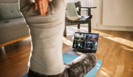 Fitness coach teaching yoga online to group of people