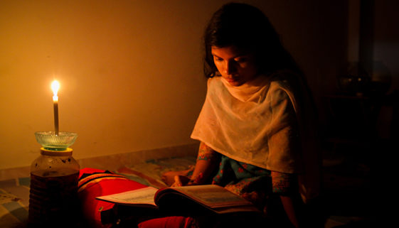 A young girl studying at home with candlelight after electricity