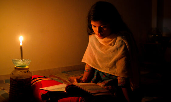 A young girl studying at home with candlelight after electricity