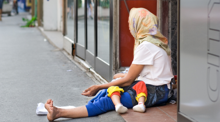 Foto de uma moça sentada no chão da rua com uma criança deitada em seu colo | São Paulo tem 526 pontos com crianças e adolescentes em situação de rua