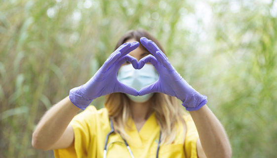 Mujer enfermera joven vestida con uniforme amarillo, guantes y m