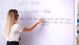 Young female english language teacher standing in front of the b