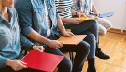 Close up view of young people sitting in chairs with folders bef