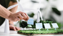 cropped view of man putting solar panels models on grass on tabl