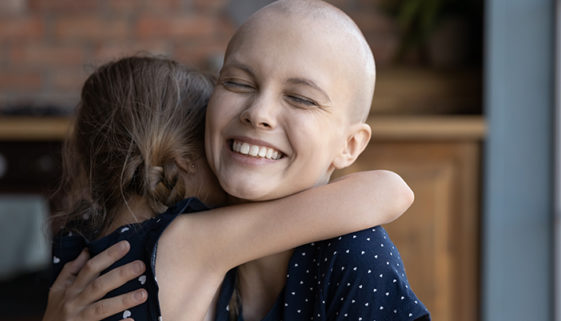 Happy excited young cancer mom embracing daughter kid