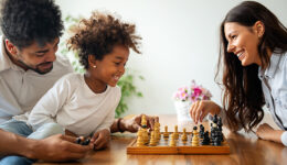 Parents and child playing chess while spending time together at home. Family love education concept