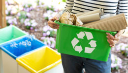 Close-up of a green basket with a recycling symbol with papers h