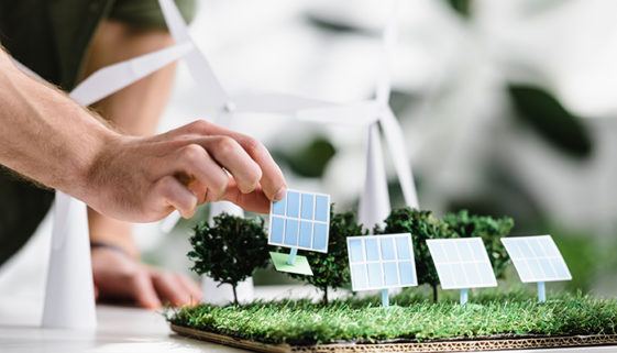 cropped view of man putting solar panels models on grass on tabl