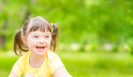 Portrait of a joyful little girl with syndrome down in a summer