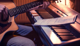 man playing acoustic guitar and piano close-up, recording notes