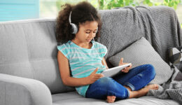 Criança ouvindo podcast em seu tablet.