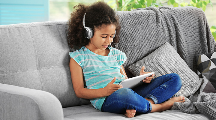 Criança ouvindo podcast em seu tablet.