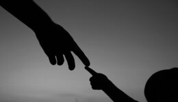 Silhoueta das mãos de um adulto e de uma criança com os dedos indicadores se tocando.
