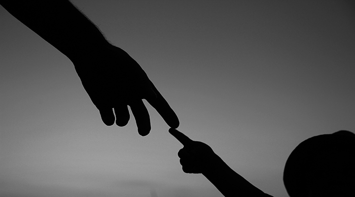 Silhoueta das mãos de um adulto e de uma criança com os dedos indicadores se tocando.