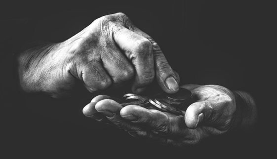 Foto em preto e branco de duas mãos, que saem de um fundo preto e contam moedas.