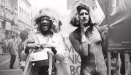 Foto em preto e branco tirada durante manifestação por direitos da comunidade LGBTQIA+ em 1970. Marsha P. Johnson e Sylvia Rivera, ativistas transexuais da época estão em primeiro plano.