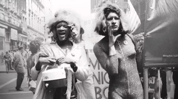 Foto em preto e branco tirada durante manifestação por direitos da comunidade LGBTQIA+ em 1970. Marsha P. Johnson e Sylvia Rivera, ativistas transexuais da época estão em primeiro plano.