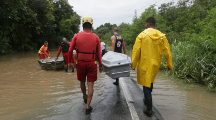Bombeiros carregam corpos de pessoas que faleceram em decorrência das enchentes. 