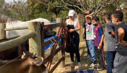 Foto de crianças e instrutora no cuidado com animais durante Terapia Assistida