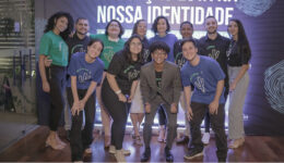 Jovens pousando para foto á frente de um telão luminoso com algumas escritas e desenhos.