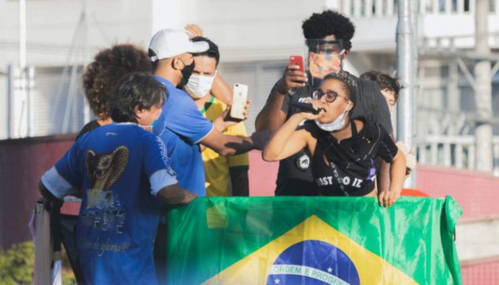 Mulher discursa em microfone junto à bandeira do Brasil