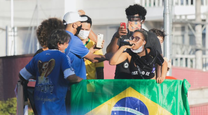 Mulher discursa em microfone junto à bandeira do Brasil