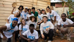 Foto de várias pessoas sorrindo e vestindo camisetas brancas com o logo da 