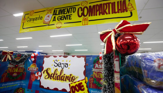 Foto de gôndola de supermercado, improvisada com papéis de temas natalinos, placas como o nome da campanha 