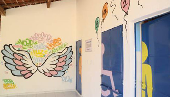 Foto de portas de banheiros e paredes brancas pintadas com desenhos de asas e bexigas coloridas