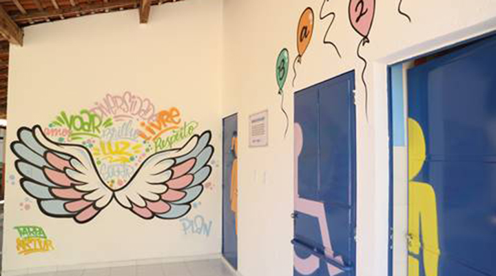 Foto de portas de banheiros e paredes brancas pintadas com desenhos de asas e bexigas coloridas