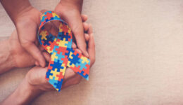 Hands holding puzzle ribbon for autism awareness