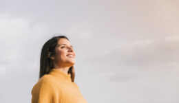 jovem-mulher-de-sorriso-que-esta-contra-o-ceu-que-olha-afastado