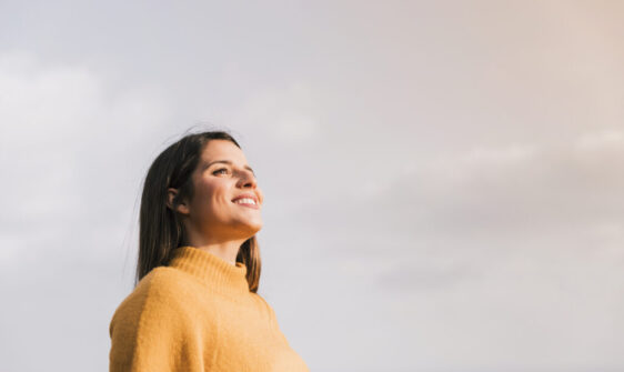 jovem-mulher-de-sorriso-que-esta-contra-o-ceu-que-olha-afastado