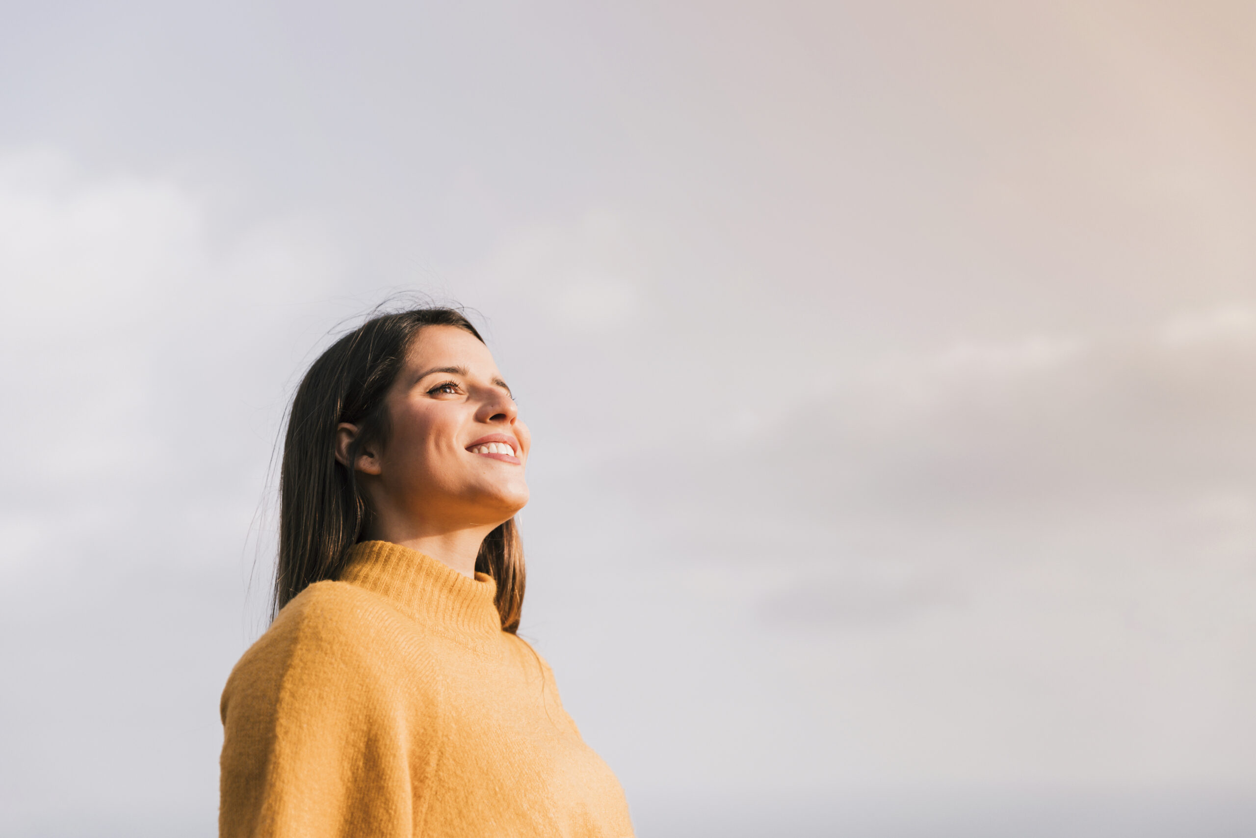 jovem-mulher-de-sorriso-que-esta-contra-o-ceu-que-olha-afastado