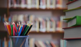 Digital composite of Pencils and stack of books with library background