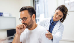 A female doctor at the clinic performs auscultation of the lungs of a patient with symptoms of coronavirus or pneumonia.