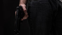Killer with gun on black background at the studio