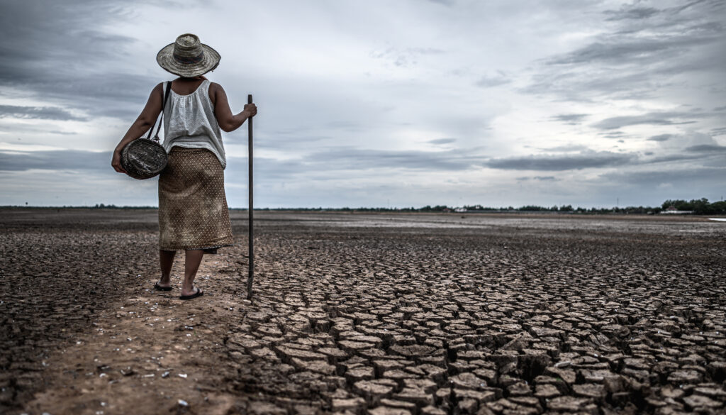 Women standing on dry soil and fishing gear, global warming and