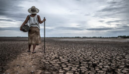 Women standing on dry soil and fishing gear, global warming and